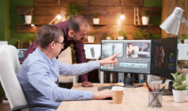 Videographer producer editing film production discussing movie graphic with photographer collegue working in creativity startup company. Focused editor man developing digital footage. Digital industry